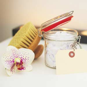 Photo of a little jar with a flower on the side and a brush in the back. click on the photo for more information about floral face scrub.